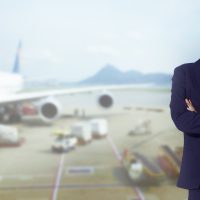 Flight attendant with scarf and dress suit, smiling at airport